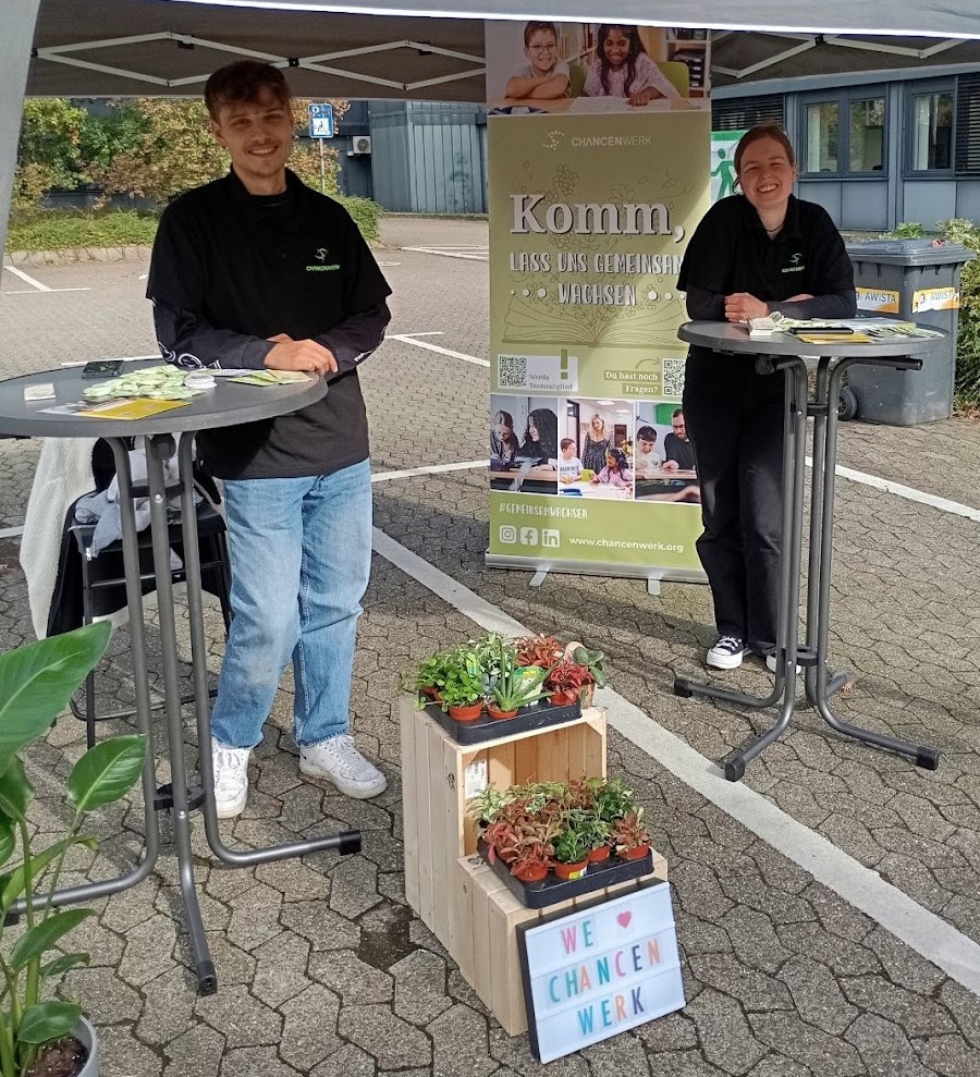 Nadine und Tom aus dem Bewerbungsmanagement Team stehen mit Pflanzen unter einem Pavillion an der Heinrich-Heine-Universität Düsseldorf