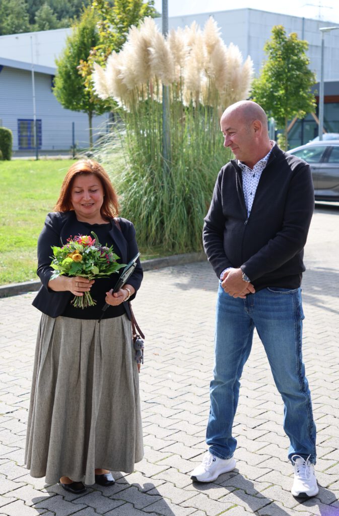 Dudu Vural wird bei der Scheckübergabe ein Blumenstrauß von Wolfgang Heller überreicht.